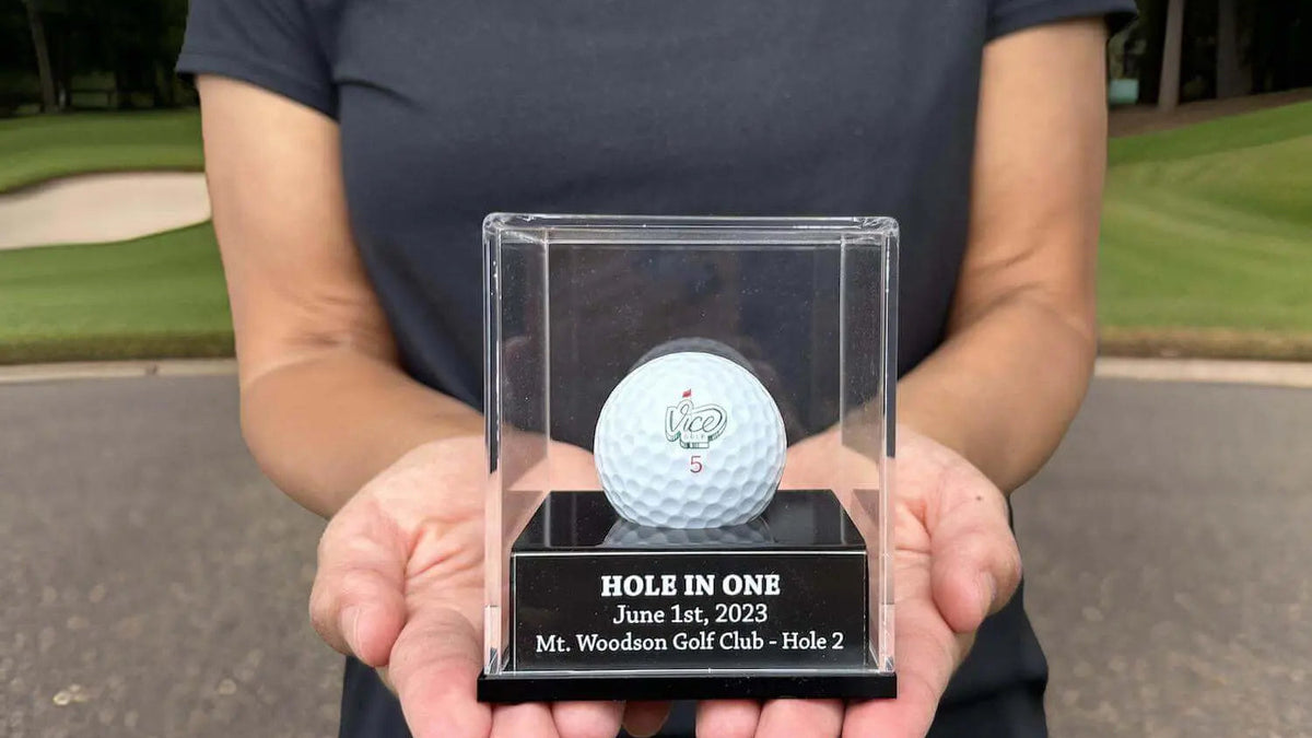 Golfer holding a custom engraved hole in one golf ball display case on a golf course
